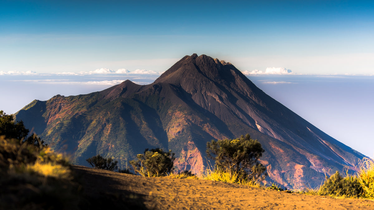 Majestic volcano peak rising above a dense layer of white clouds