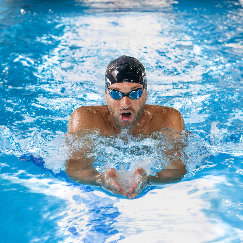 Professional male swimmer wearing goggles and cap training in pool