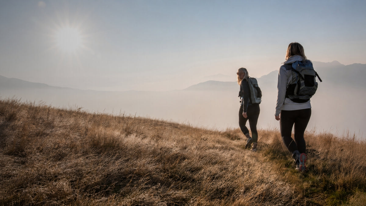 Two hikers with backpacks trekking up a steep foggy mountain trail