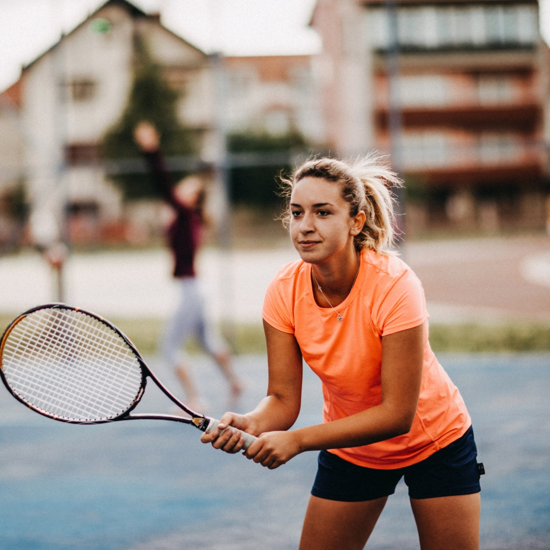 Focused female tennis player holding racket on clay court outdoors